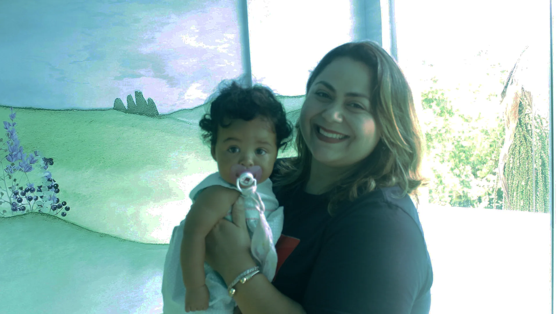 Uma voluntária do GUIA Kids com um bebê no colo, sorrindo